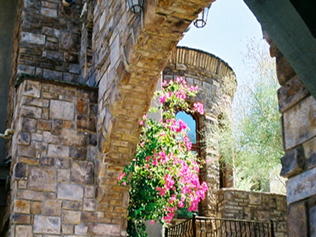Exterior stone wainscot and column wrap on a stucco home facade