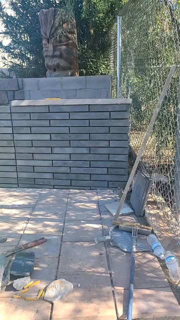 Charcoal linear stone garden wall completed beside a carved stone figure in a Tempe yard
