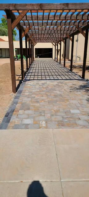 Multicolor stone paver walkway running beneath a timber pergola